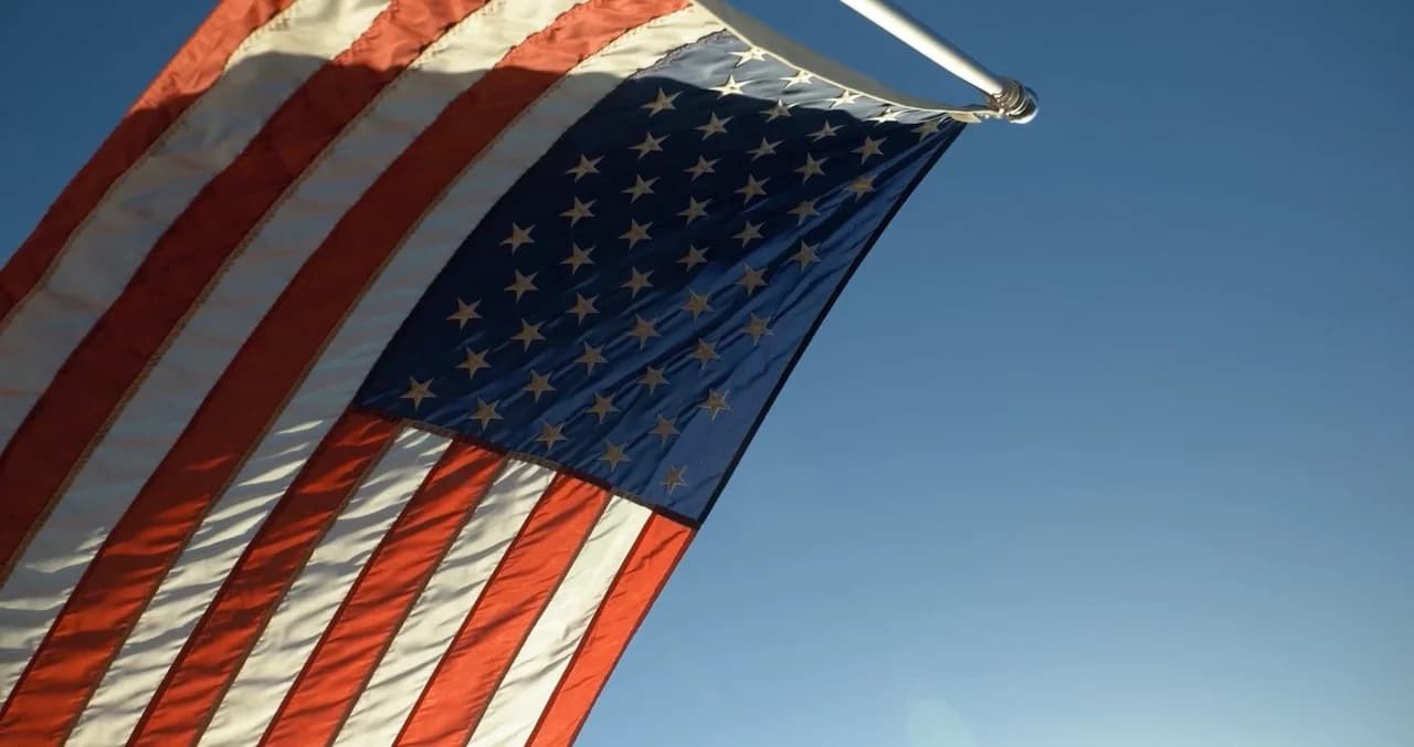 Slow motion cinematic American flag waving gracefully over federal architectural backdrop